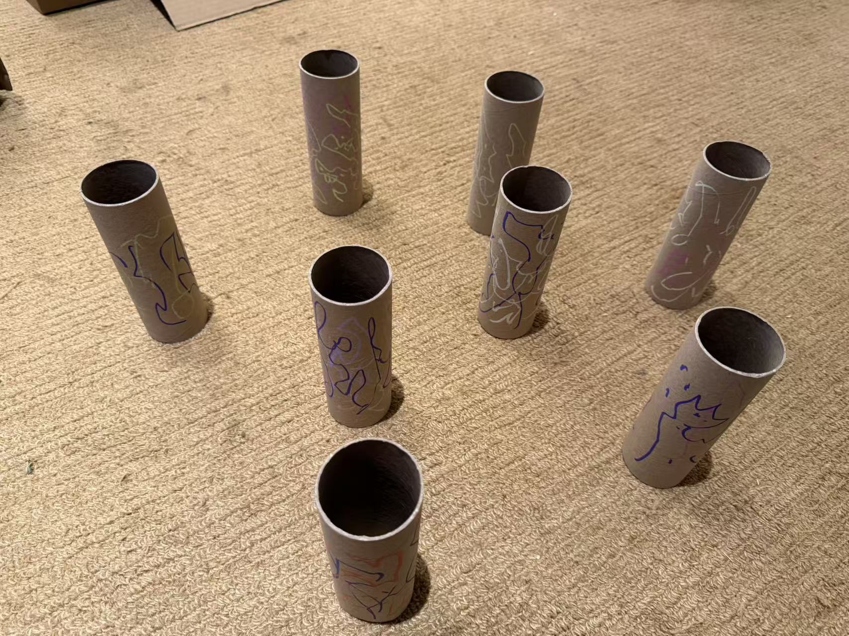 A group of cardboard tubes decorated with children's drawings.