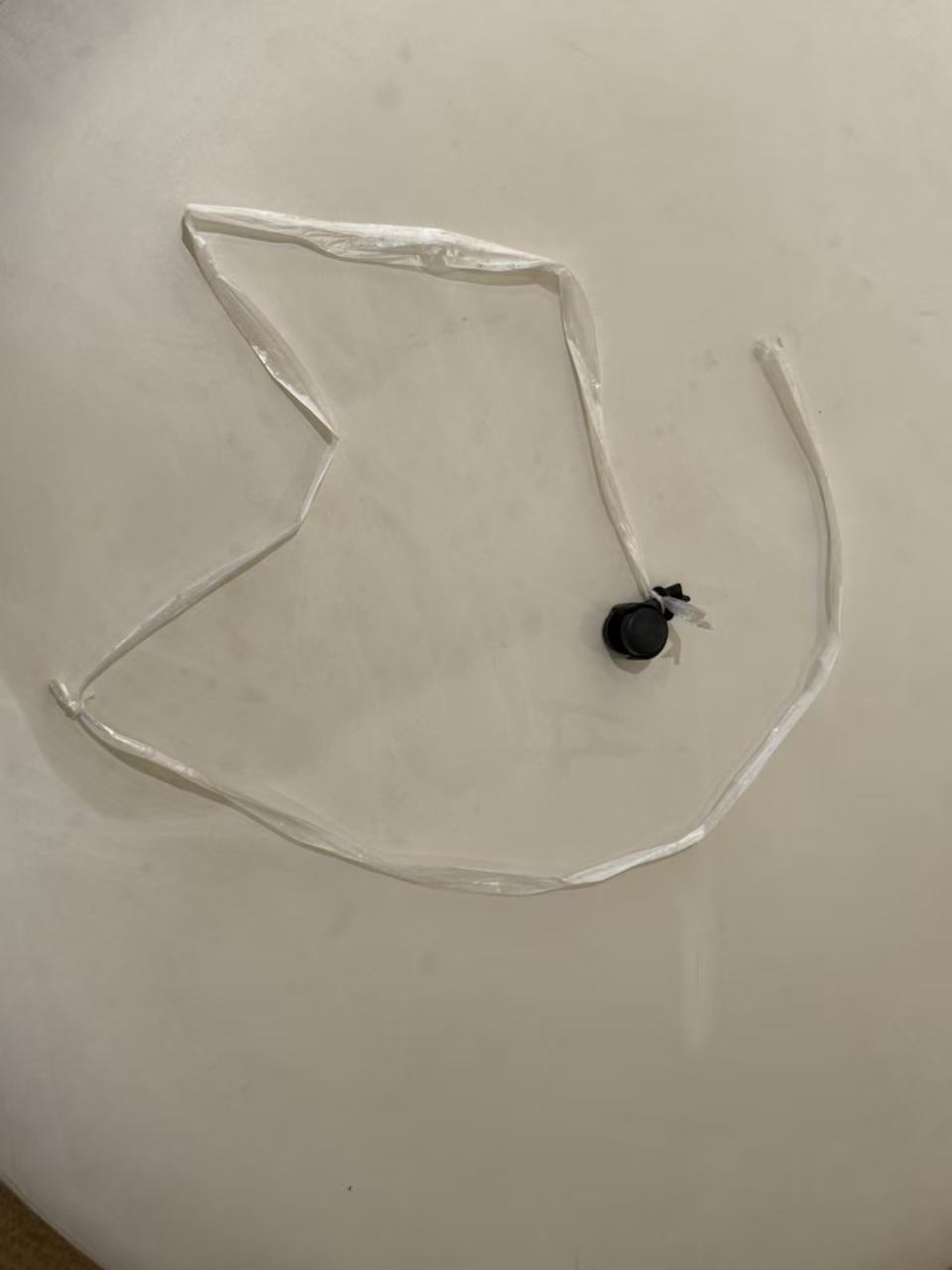 A small black caster attached to a long pulling strip.