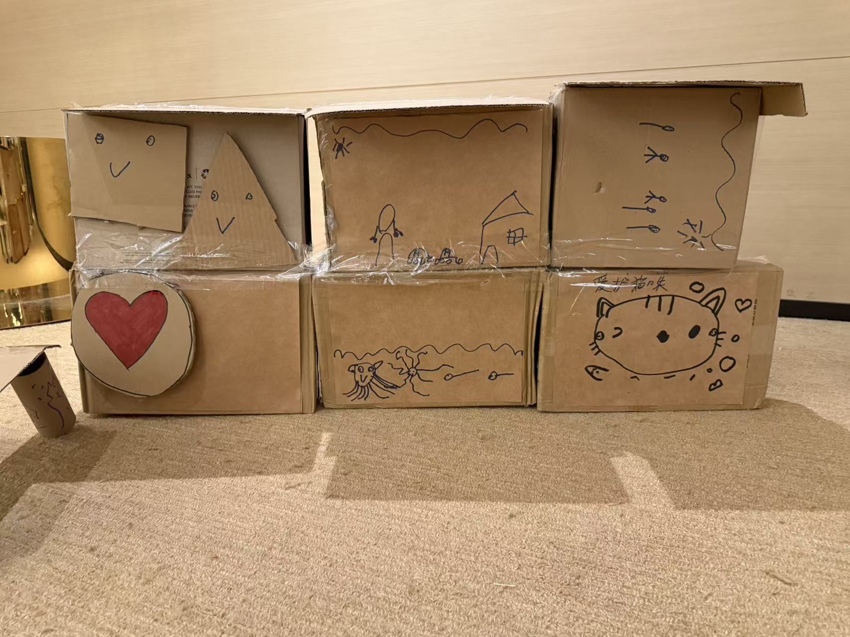 Another view of the children's drawings on the front of the cardboard structure.