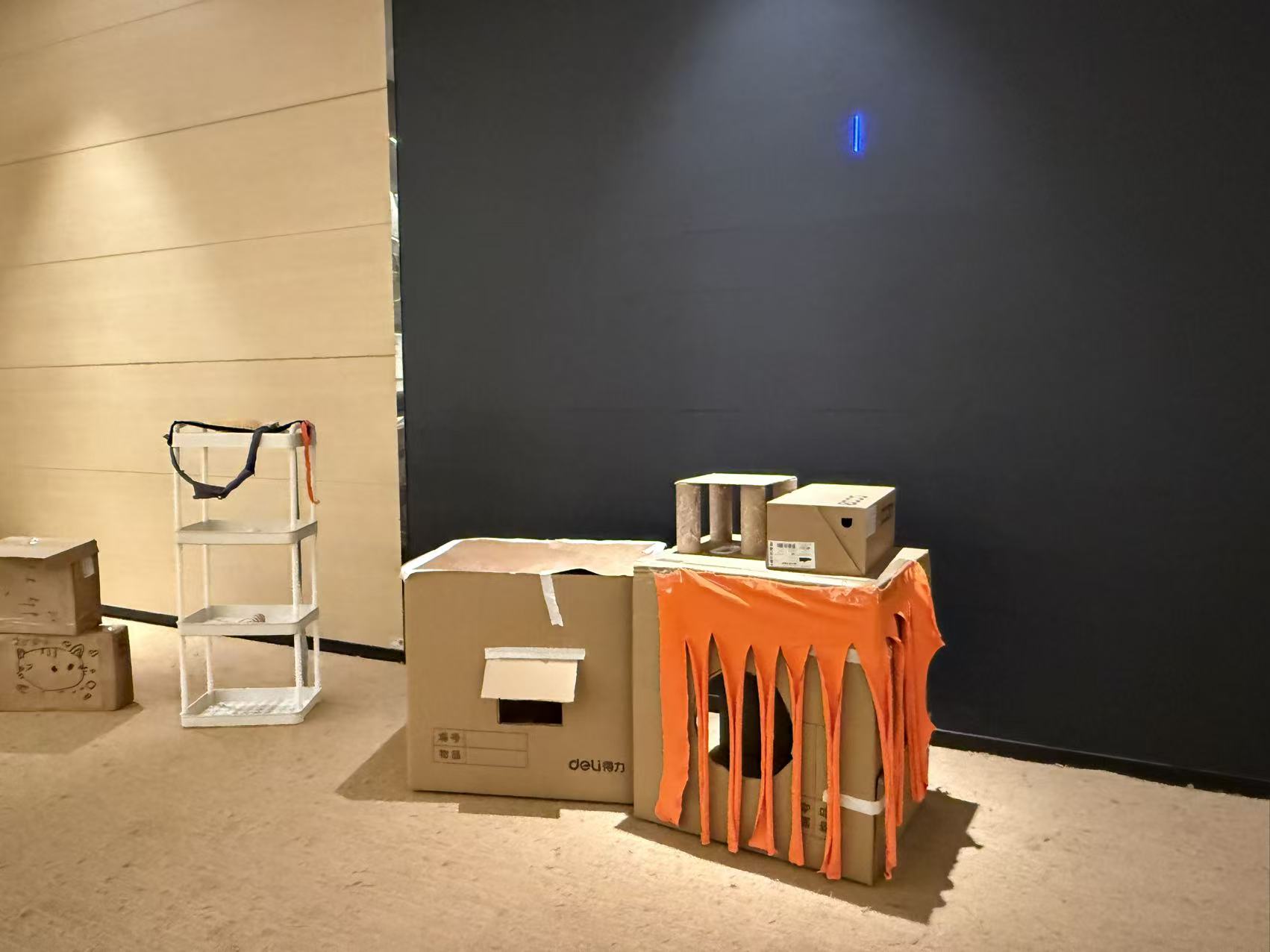 A cardboard cat house with an orange fabric curtain across its entrance.